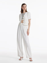 A lady wears a tank top and a white jean jacket.